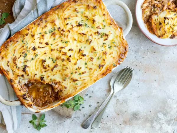 Golden fork-ridged mashed potato crust on a freshly baked British fish pie in a white oven dish.