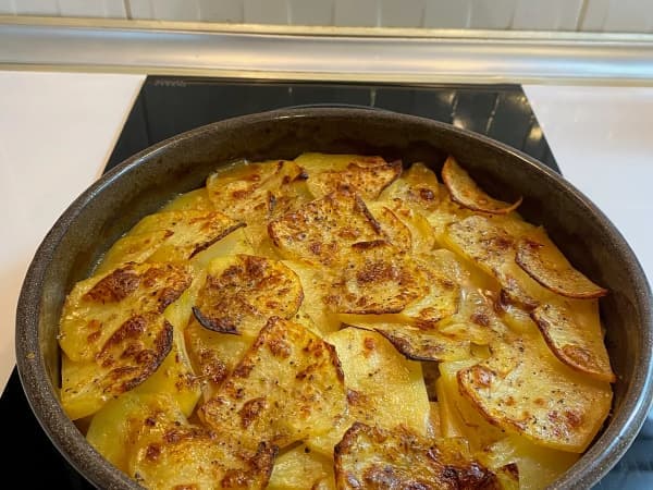 Traditional Lancashire hotpot in a round casserole dish with crisp, golden overlapping sliced potatoes and rich bubbling juices