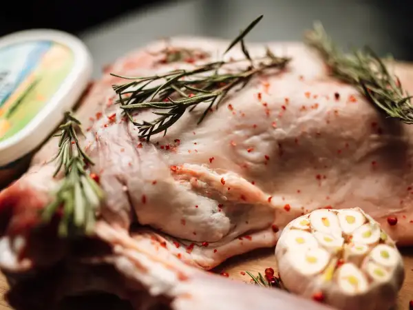 Fresh ingredients for Lancashire hotpot: lamb neck chops, fresh rosemary and thyme, butter and garlic arranged for cooking