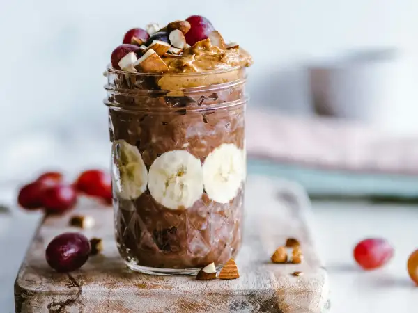Swollen creamy overnight oats in a glass jar topped with freshly sliced banana and berries