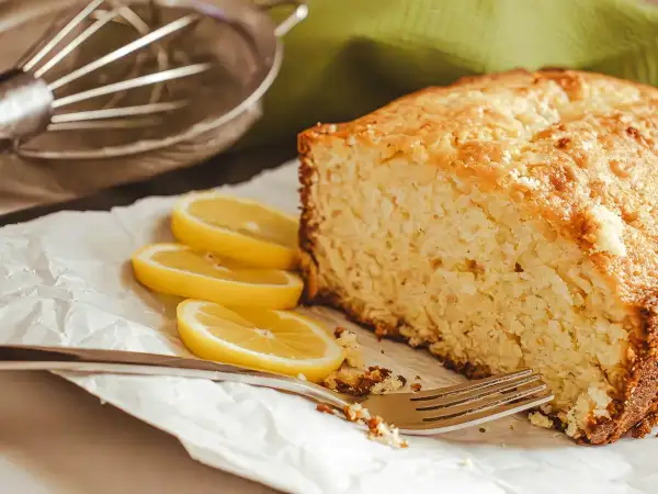 Moist sliced lemon drizzle loaf cake displaying tender pale yellow crumb and crisp speckled sugar topping
