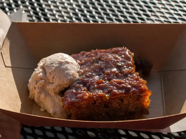 Warm square slice of classic British sticky toffee date pudding covered in glossy homemade toffee sauce