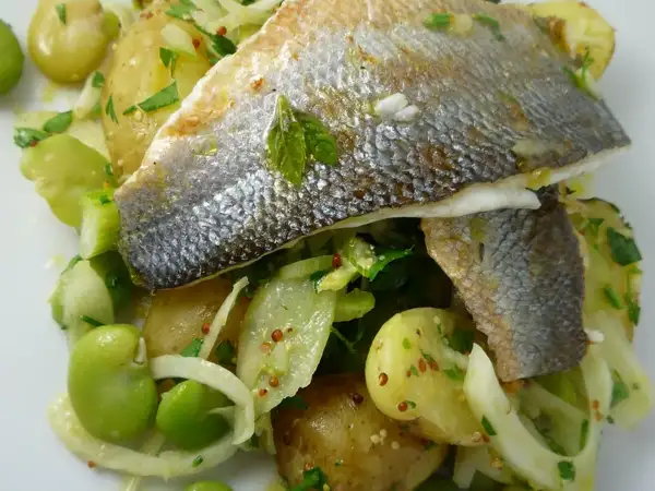 Herby mustard dressed new potato salad served alongside pan-seared fish on a summer British dining table