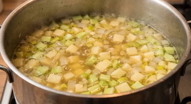 Diced potato and broccoli stalk simmering gently in vegetable stock in a covered saucepan.